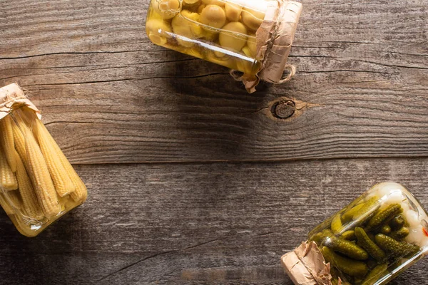 Top view of delicious homemade tasty pickled cucumbers, corn and mushrooms on wooden rustic table — Stock Photo