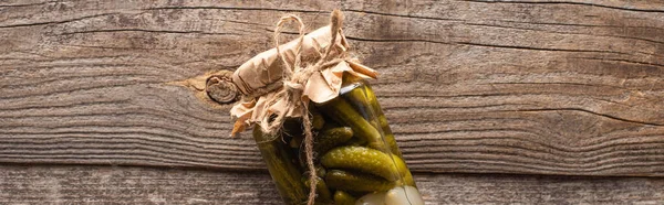 Top view of homemade tasty canned cucumbers in jar on wooden table, panoramic shot — Stock Photo