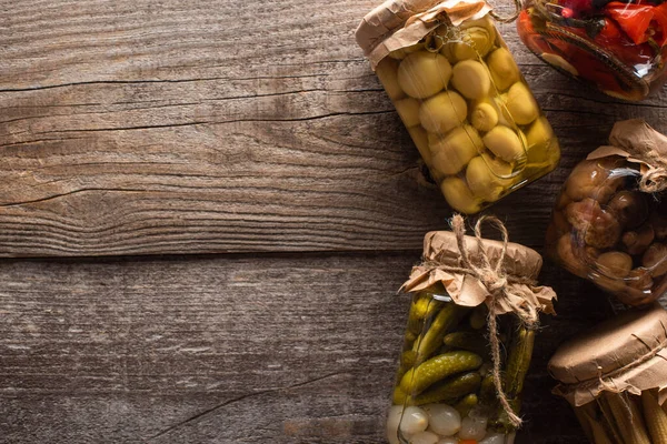 Vue de dessus des cornichons savoureux faits maison dans des bocaux sur la table en bois — Photo de stock