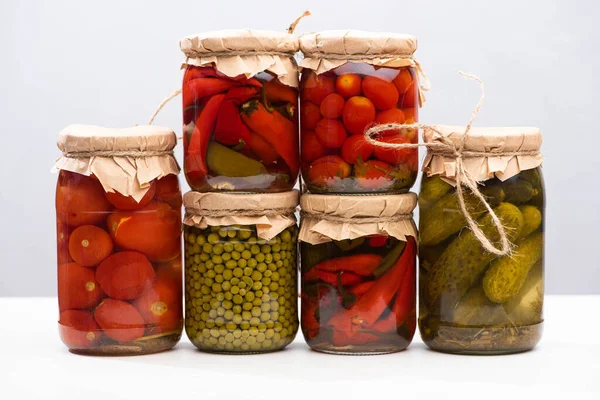 Cornichons délicieux faits maison dans des pots isolés sur gris — Photo de stock