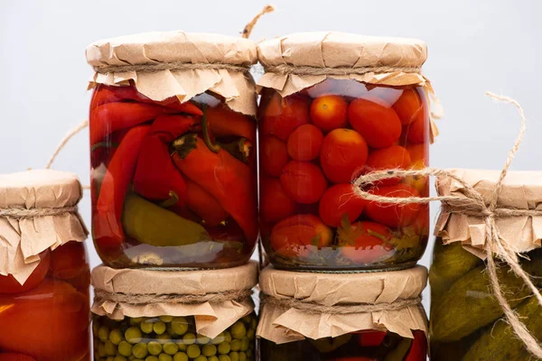 Deliciosos encurtidos caseros en frascos aislados en gris - foto de stock