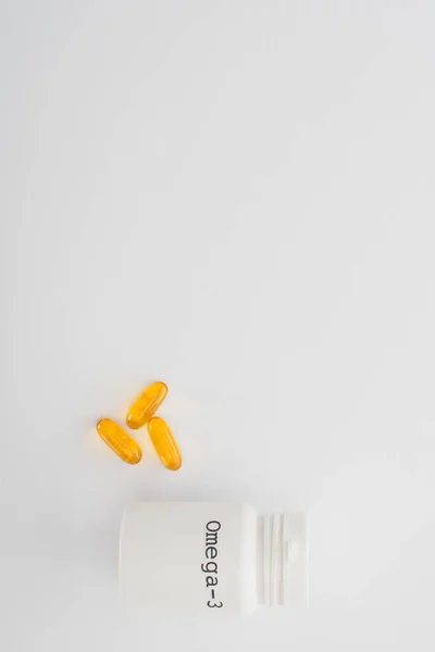 Vue du dessus du récipient avec lettrage oméga-3 et capsules sur blanc — Photo de stock