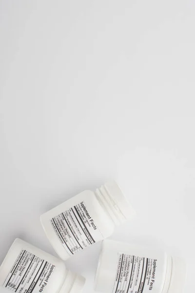 Draufsicht auf Behälter mit Nahrungsergänzungsmitteln auf weiß — Stockfoto
