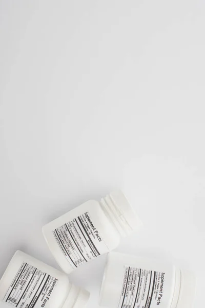 Top view of containers with dietary supplements on white — Stock Photo