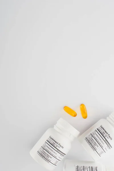 Top view of containers and fish oil capsules on white background — Stock Photo