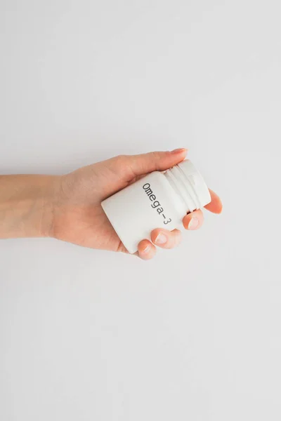 Cropped view of woman holding container with omega-3 lettering on white background — Stock Photo