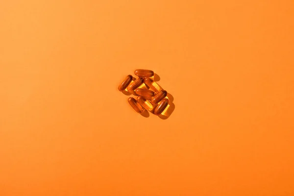 Top view of brown capsules on orange background — Stock Photo