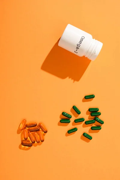 Vista dall'alto del contenitore con scritta omega-3 e capsule su arancione — Foto stock