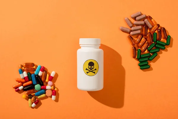 Top view of container with dangerous poison and dietary supplements on orange background — Stock Photo