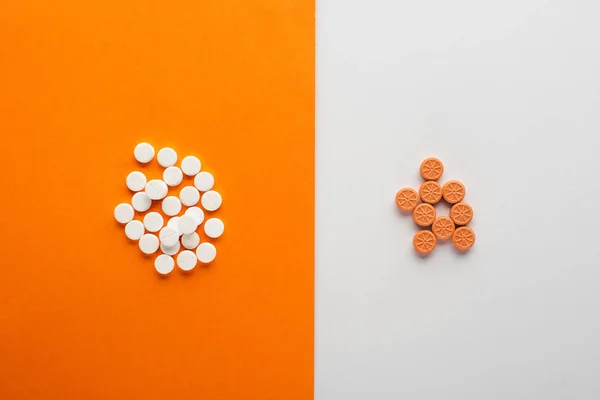 Vista superior de las píldoras sobre fondo blanco y naranja - foto de stock