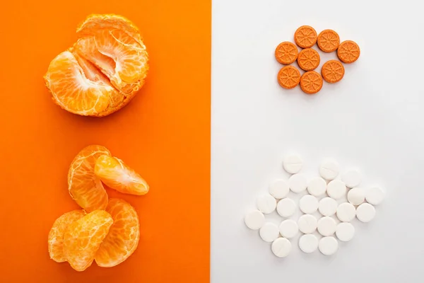 Top view of dietary supplements and mandarin on white and orange — Stock Photo