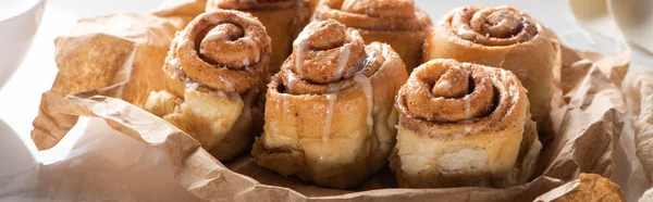 Close up view of fresh homemade cinnamon rolls on parchment paper, panoramic shot — Stock Photo