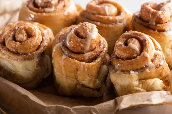 Vue rapprochée de délicieux rouleaux de cannelle maison frais sur papier parchemin — Photo de stock