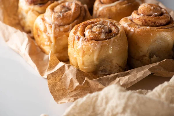 Vue rapprochée de délicieux rouleaux de cannelle maison frais sur papier parchemin — Photo de stock