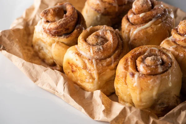 Vue rapprochée de délicieux rouleaux de cannelle maison frais sur papier parchemin — Photo de stock