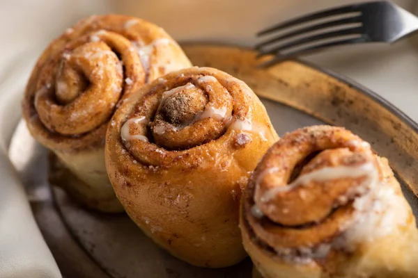 Vue rapprochée des rouleaux de cannelle frais faits maison à bord sur tissu satiné avec fourchette — Photo de stock