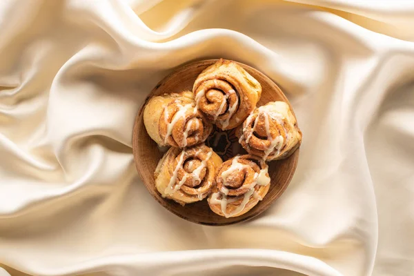 Top view of fresh homemade cinnamon rolls on silk white cloth — Stock Photo