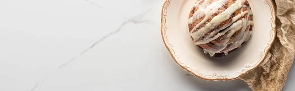 Top view of fresh homemade cinnamon roll on plate on marble surface with cloth, panoramic shot — Stock Photo