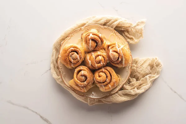 Top view of fresh homemade cinnamon rolls on marble surface with cloth — Stock Photo