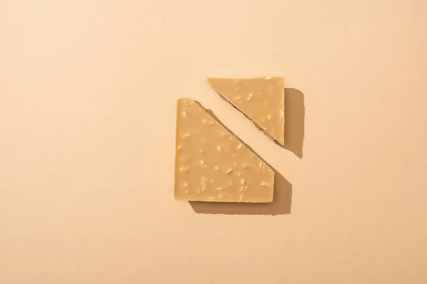 Top view of delicious broken white chocolate bar on beige background — Stock Photo