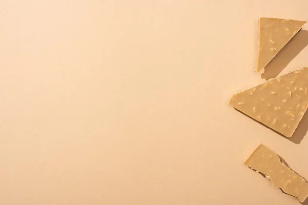 Top view of delicious broken white chocolate bar on beige background — Stock Photo