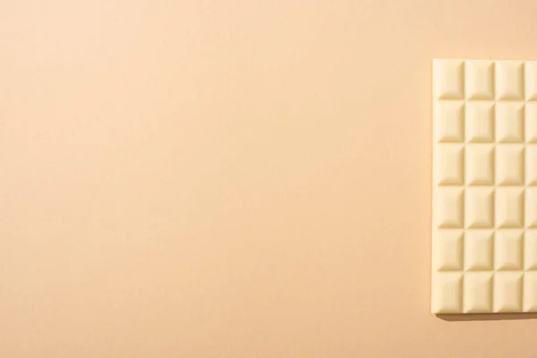 Vista dall'alto di deliziosa barretta di cioccolato bianco su sfondo beige — Foto stock