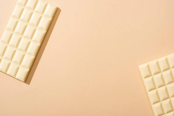 Vista dall'alto di deliziose barrette di cioccolato bianco su sfondo beige — Foto stock