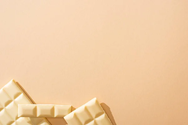 Vista dall'alto di deliziosa barra di cioccolato bianco rotto su sfondo beige — Foto stock