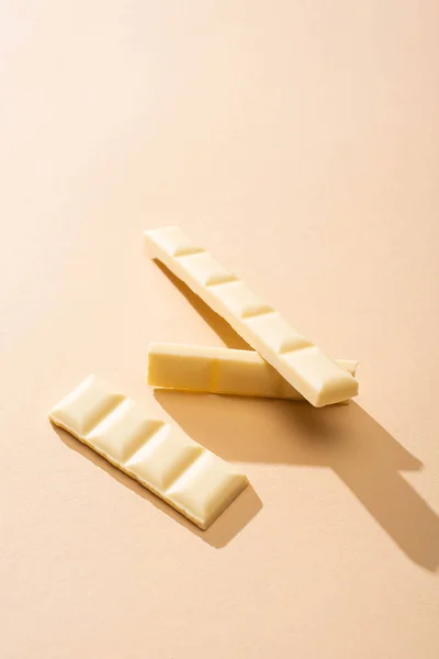 Сладкий вкусный сломанный белый шоколад на бежевом фоне — стоковое фото
