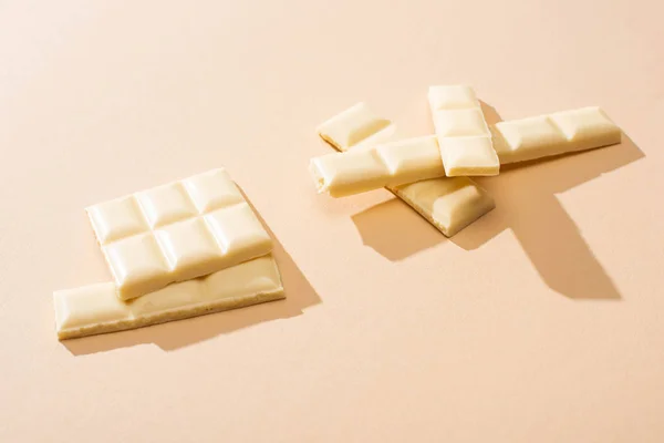 Süße köstliche gebrochene weiße Schokolade Riegel auf beigem Hintergrund — Stockfoto