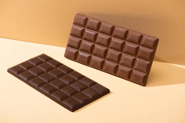 Dulce delicioso oscuro, barras de chocolate con leche sobre fondo beige - foto de stock