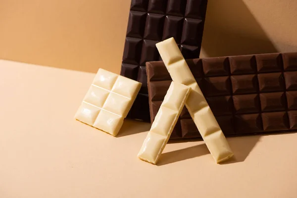 Sweet delicious dark, milk and white chocolate on beige background — Stock Photo