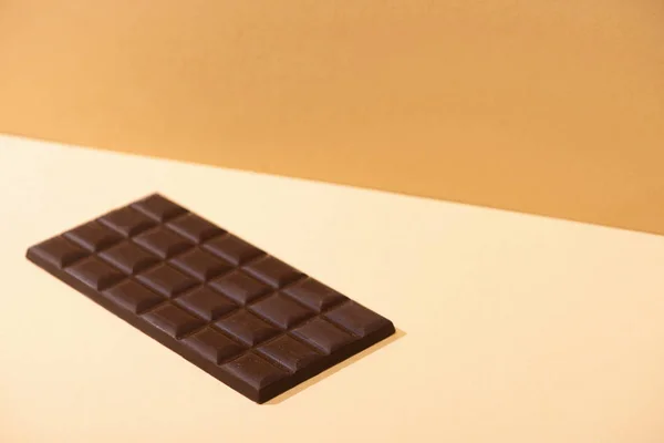 Barre de chocolat noir délicieux sucré sur fond beige — Photo de stock