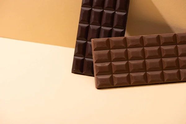 Dolce delizioso fondente, barrette di cioccolato al latte su sfondo beige — Foto stock