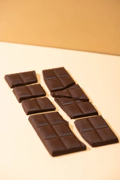 Délicieux chocolat noir cassé sucré sur fond beige — Photo de stock