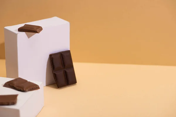 Deliciosas piezas de chocolate oscuro y leche y cubos cuadrados sobre fondo beige - foto de stock