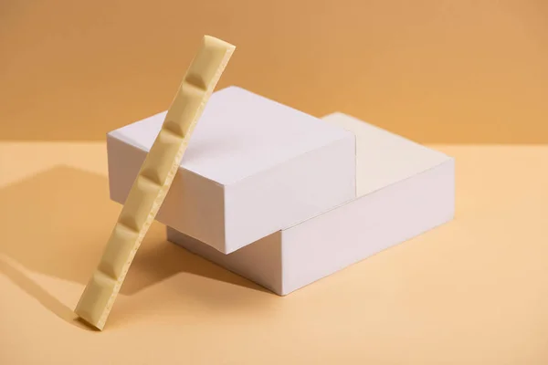 Delizioso pezzo di cioccolato bianco e cubetti su sfondo beige — Foto stock