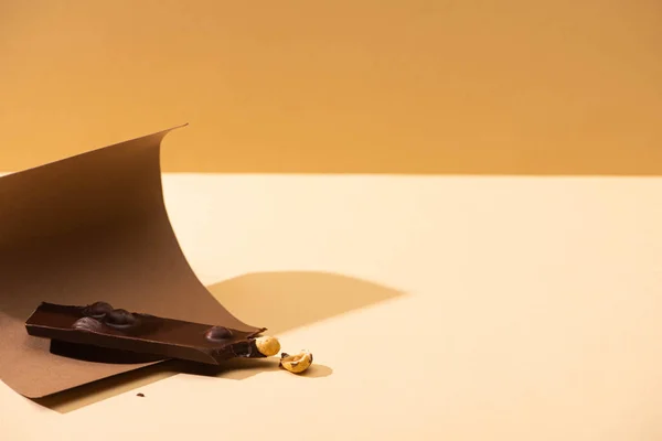 Délicieux chocolat noir avec morceau de noix, papier sur fond beige — Photo de stock