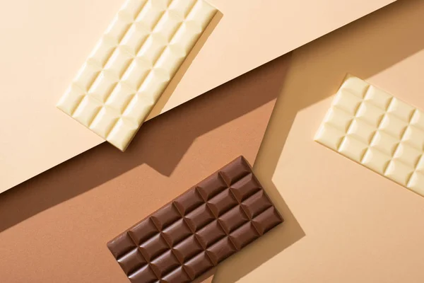 Top view of delicious whole white and milk chocolate bars on beige background — Stock Photo