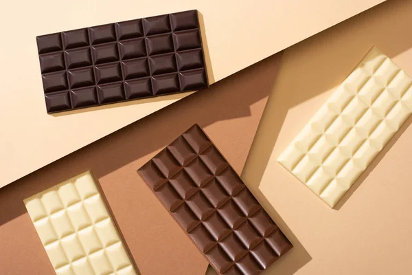 Vue du dessus de délicieuses barres de chocolat au lait entier, blanc et noir sur fond beige — Photo de stock