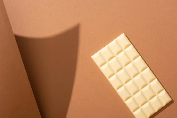 Selective focus of delicious whole white chocolate bar on brown background with paper — Stock Photo