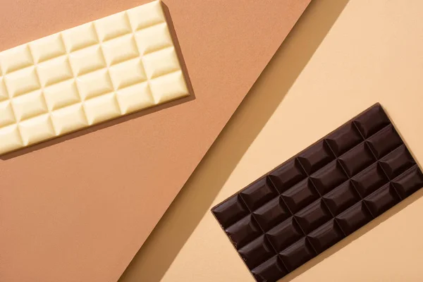 Vista dall'alto di deliziose barrette di cioccolato bianco e fondente su sfondo beige — Foto stock