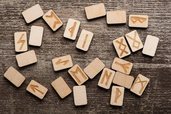 Top view of wooden runes with ethnic signs on wooden surface — Stock Photo