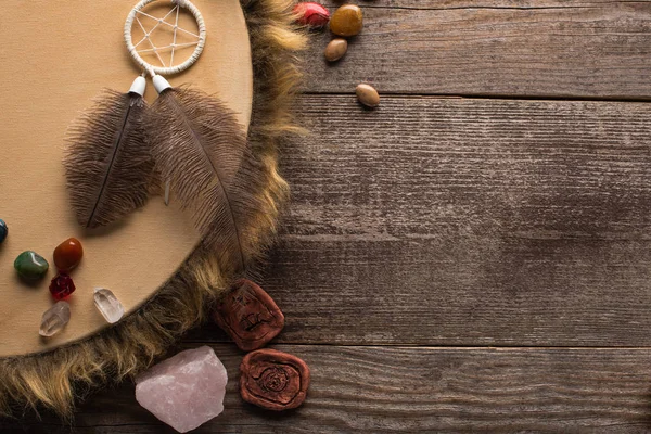 Vista dall'alto di tamburello sciamanico, acchiappasogni e cristalli magici su sfondo di legno — Stock Photo