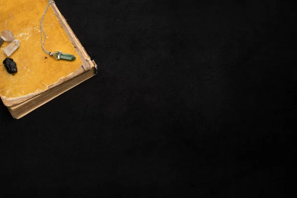 Magical crystals on book isolated on black — Stock Photo