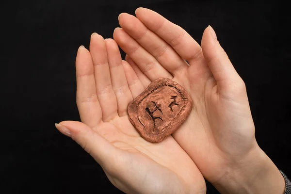 Cropped view of shaman holding clay amulet with signs isolated on black — Stock Photo