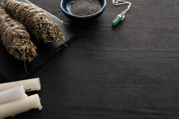 Candles, smudge sticks with crystal and bowl of ash on dark wooden surface — Stock Photo