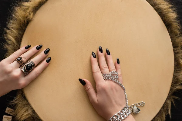 Vue du dessus du chaman avec accessoires bijoux sur les mains jouant sur tambourin isolé sur noir — Photo de stock