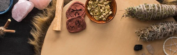 Top view of smudge sticks and crystals, dreamcatcher and clay amulets on tambourine on dark wooden surface, panoramic shot — Stock Photo