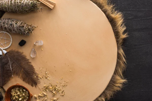 Vista dall'alto di bastoncini sciamanici, acchiappasogni e cristalli magici su tamburello su sfondo di legno scuro — Foto stock